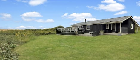A single-story building with a flat roof, a covered porch, and a small deck.