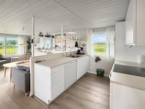 A modern kitchen with white cabinetry, a built-in dishwasher, and a window overlooking greenery. - "Steffenie" - 400m from the sea by Interhome (Løkken)