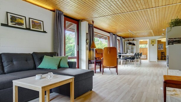 Una sala moderna con un sofá, una mesa de centro y una zona de comedor con sillas y una mesa.
