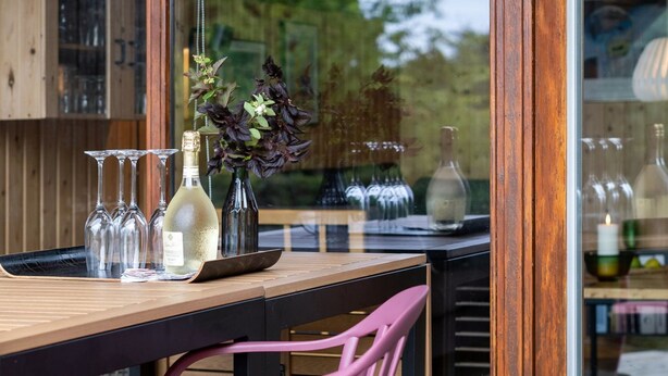 A wooden table with wine glasses, a bottle, and a vase with flowers. - "Ija" - 200m from the sea by Interhome (Føllenslev)