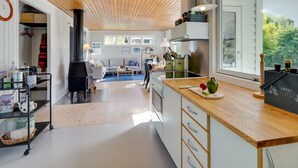 A modern kitchen with wooden cabinets, a central island, and a large window providing natural light. - "Gærmund" - 350m from the sea by Interhome (Føllenslev)