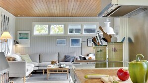 A modern kitchen with wooden countertops, a cutting board with vegetables, and a dining area with a sofa and coffee table. - "Gærmund" - 350m from the sea by Interhome (Føllenslev)