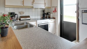 Et moderne køkken med granitbordplader, rustfrie stålapparater og hvide skabe.