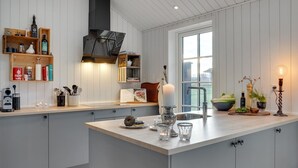Une cuisine moderne dotée d’un îlot central, d’étagères en bois et offrant une vue sur l’extérieur.