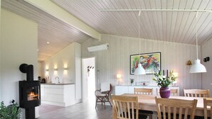 A modern kitchen with white cabinets, a black stove, and a dining area with wooden chairs and a table.