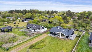 An aerial view of a residential area with houses, lawns, and a dirt path.