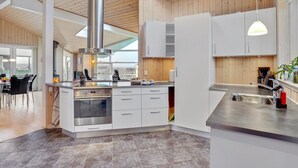 A modern kitchen with a central island, stainless steel appliances, and a skylight.