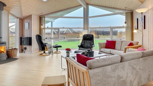 A spacious living room with a fireplace, large windows, and a view of the outdoors.