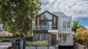 A modern two-story house with a balcony, a garage, and a fenced garden area. - StayCentral - Thornbury Townhouse (Thornbury)