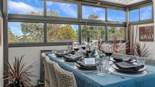 A dining table set for six with a blue tablecloth, wine glasses, and a bottle of wine. - StayCentral - Thornbury Townhouse (Thornbury)