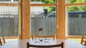A dining table with chairs, a small flag, and a window with a view of a fence and trees. - "Linda" - 600m from the sea by Interhome (Sjællands Odde)