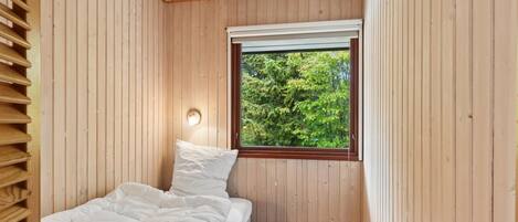 A bedroom with a bed, a window, and a small black speaker.