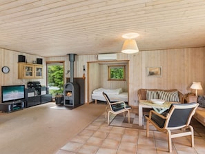 Interior acogedor de una cabaña con chimenea, paredes de madera, un televisor y un comedor.