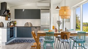 Una cocina moderna con armarios grises, una isla central y un comedor con sillas azul turquesa y una mesa de madera.