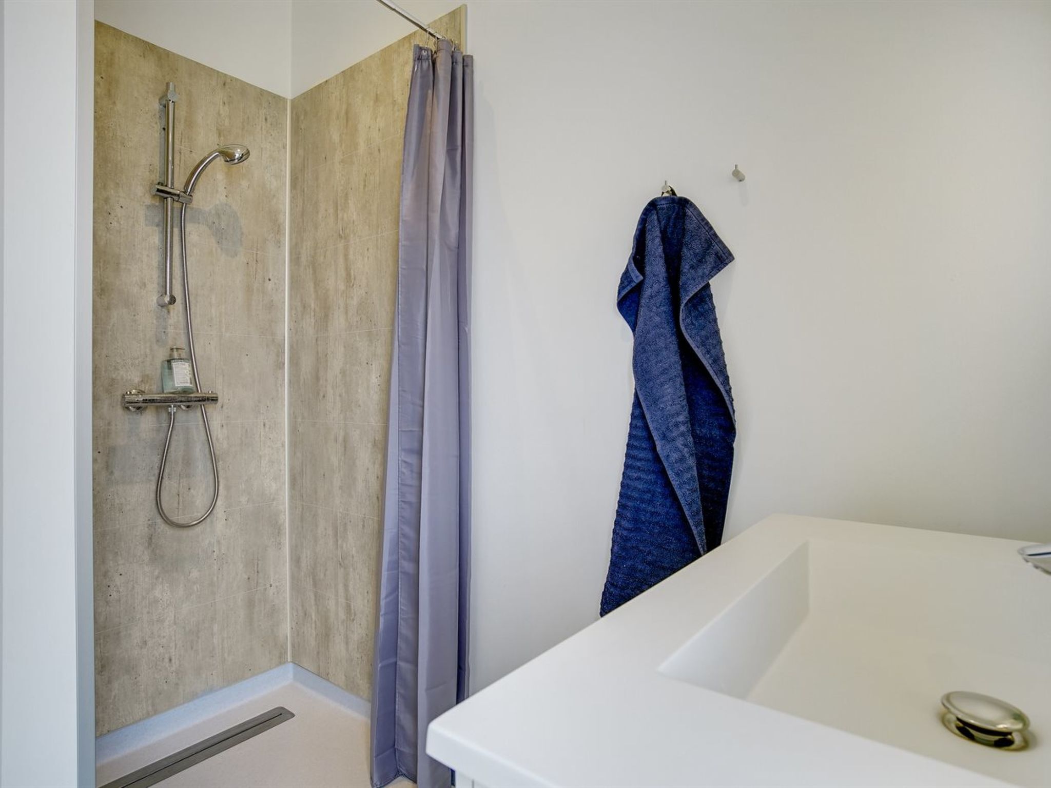 A modern bathroom with a shower, a bathtub, and a towel hanging on the wall.