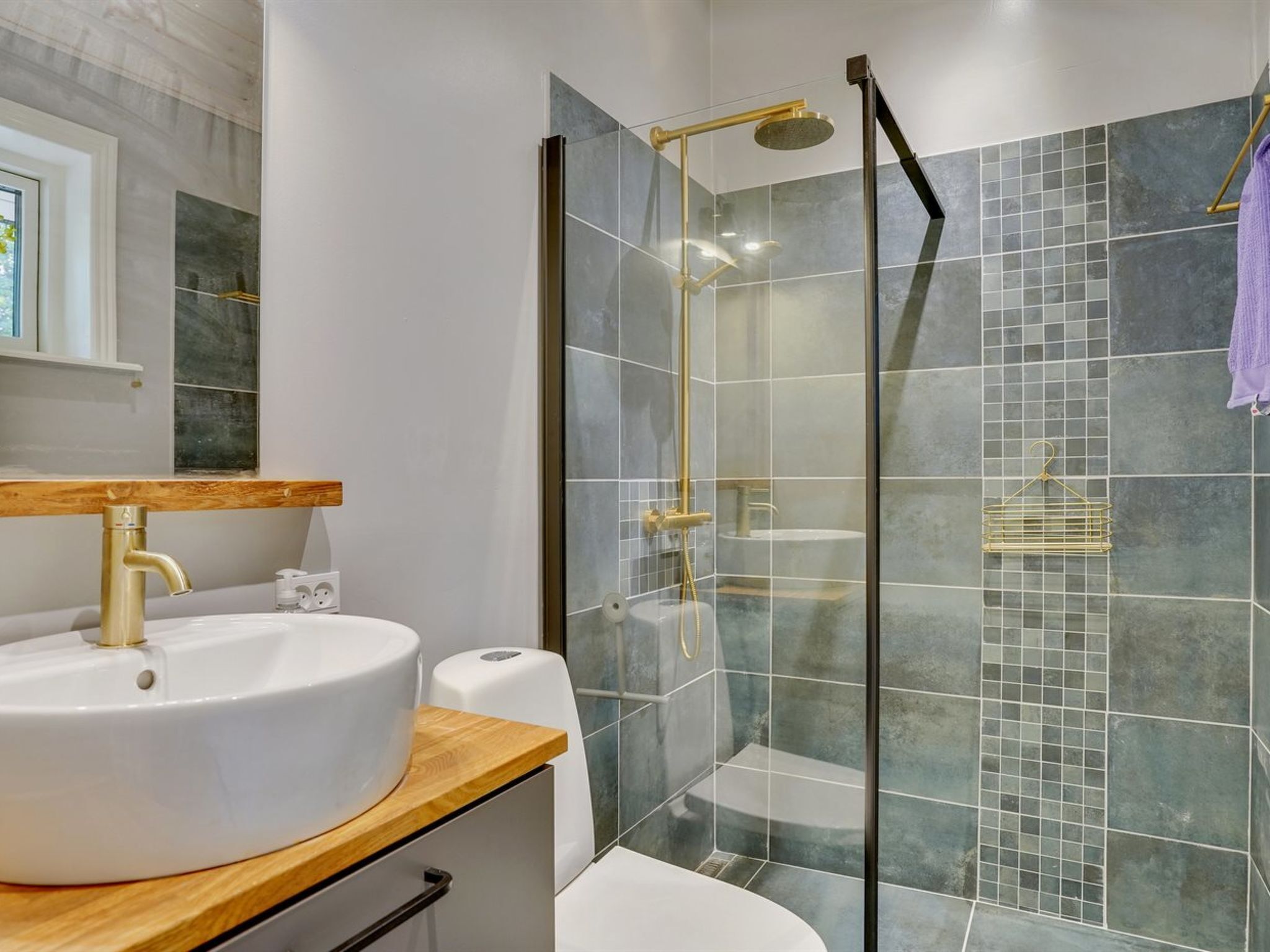 Een moderne badkamer met een glazen douchecabine, een wit wastafelmeubel met houten blad en een grote spiegel.