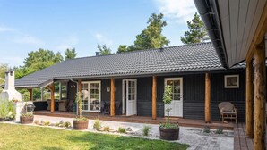 Une maison dotée d’un patio couvert, d’un espace barbecue et d’une pelouse bien entretenue.
