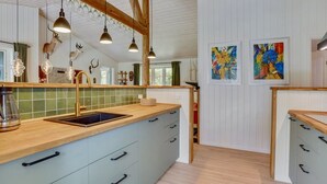 Une cuisine dotée d’un îlot central, de luminaires suspendus et d’un plafond en bois.