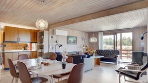 Ein modernes Interieur mit Essbereich, einer Couch und Blick ins Freie.