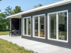 Ett modernt hus med stora fönster och en täckt uteplats.