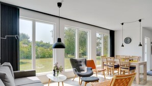 A modern living room with a sofa, armchair, and dining area with chairs and a table.