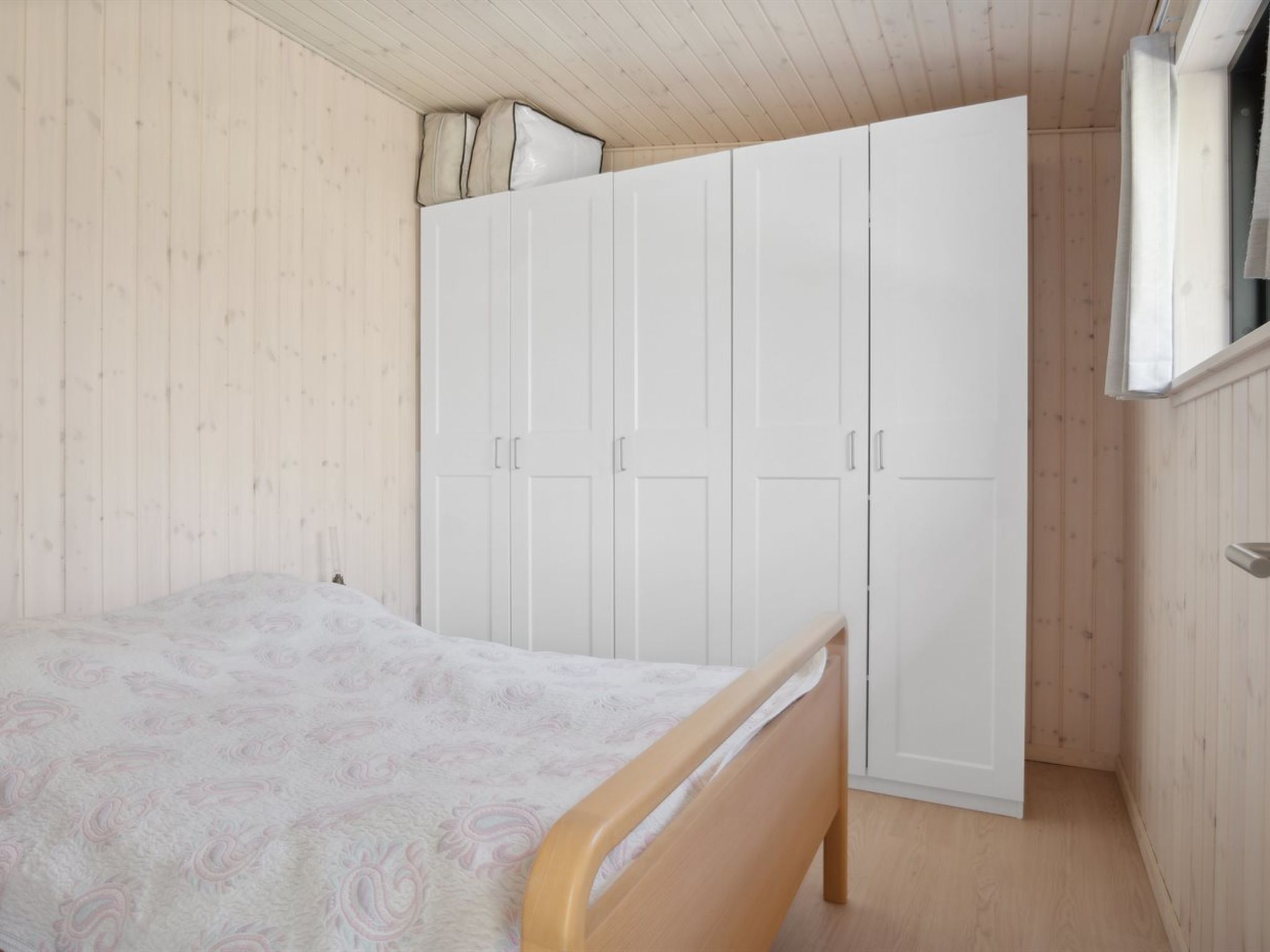 A bedroom with a bed, a wardrobe, and a window.