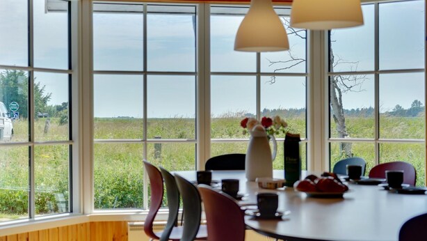 A dining area with a large window, a table with chairs, and a vase with flowers.