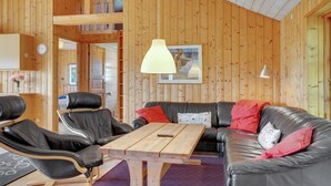 A cozy cabin interior with a wooden interior, a dining table, leather chairs, and a sofa.