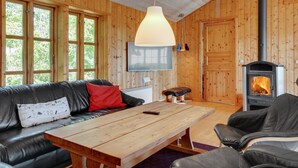 A cozy cabin interior with a wooden interior, a fireplace, a sofa, and a table.