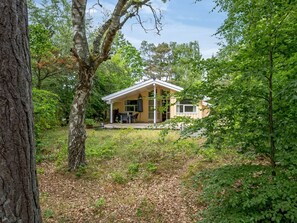 A small cabin with a porch, surrounded by trees.