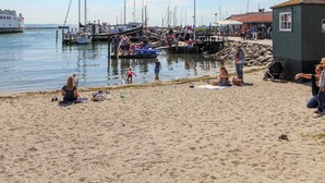 A beach with people, boats, and a small building.