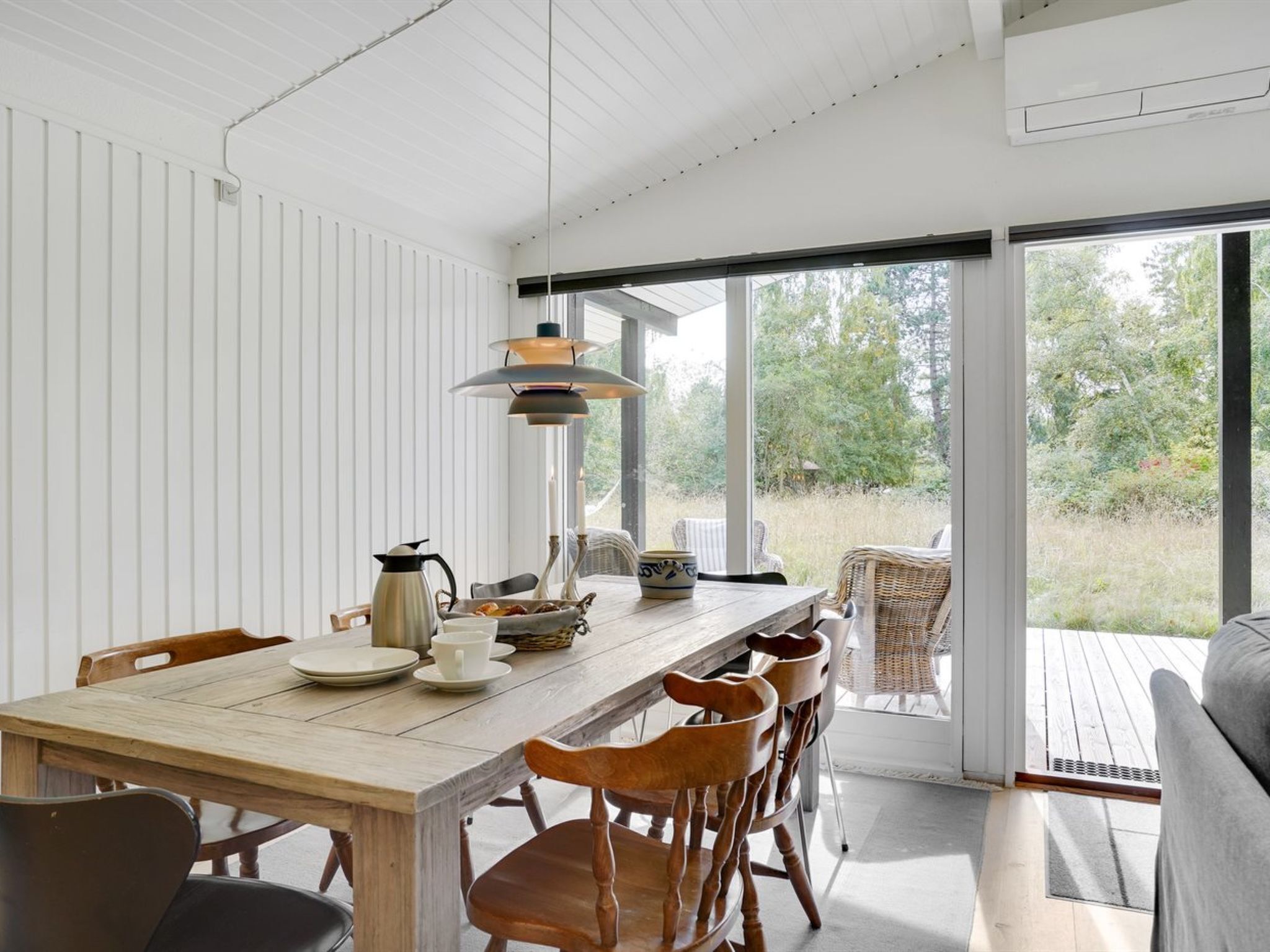 Un coin repas avec une table en bois, des chaises et un luminaire suspendu.