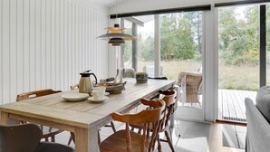 A dining area with a wooden table, chairs, and a hanging light fixture.