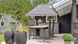 A wooden deck with a table and chairs, surrounded by potted plants. - "Elayne" - 3km from the sea by Interhome (Blokhus)