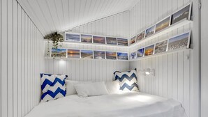 A bedroom with a bed, two pillows, a wall-mounted shelf with photos, and a hanging plant. - "Elayne" - 3km from the sea by Interhome (Blokhus)