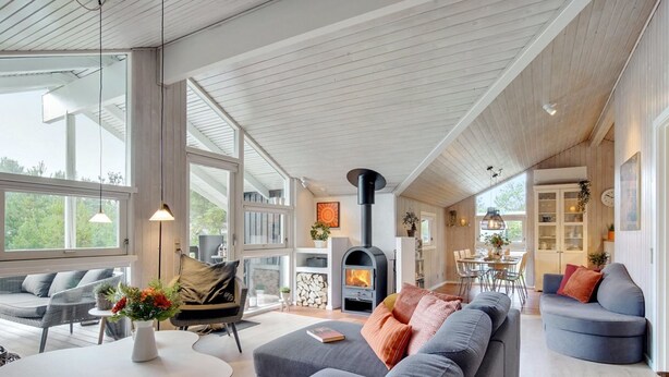 A spacious living area with a large sofa, a dining table, and a wood-burning stove. - "Elayne" - 3km from the sea by Interhome (Blokhus)