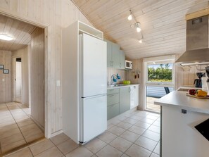 A modern kitchen with white cabinetry, a built-in microwave, and a large window providing a view of the outdoors.