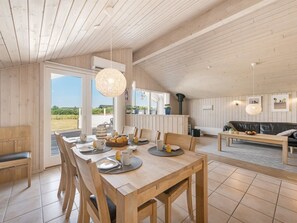 A spacious dining area with a wooden table set for breakfast, a sofa in the living area, and a view of the outdoors. - "Claudius" - 1.3km to the fjord by Interhome (Tarm)