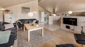 Een ruime woonkamer met een bank, salontafel en een open haard.