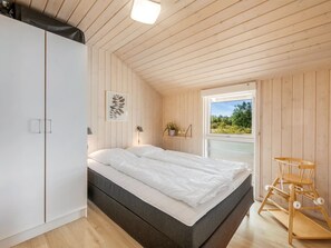 A bedroom with a bed, wardrobe, bedside table, lamp, and a view through a window. - "Claudius" - 1.3km to the fjord by Interhome (Tarm)