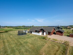 A residential property with a large lawn, a trampoline, and a house with a sloped roof. - "Claudius" - 1.3km to the fjord by Interhome (Tarm)