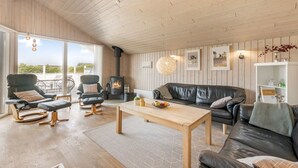 Een ruime woonkamer met een open haard, leren banken en een eettafel.