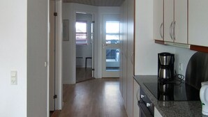 A kitchen with wooden flooring, a coffee maker, and a dishwasher.