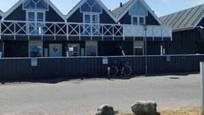 A building with a dark facade, multiple windows, and a bicycle parked in front.