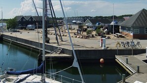 A marina with a sailboat docked, a small docked boat, and a building with a sloped roof.