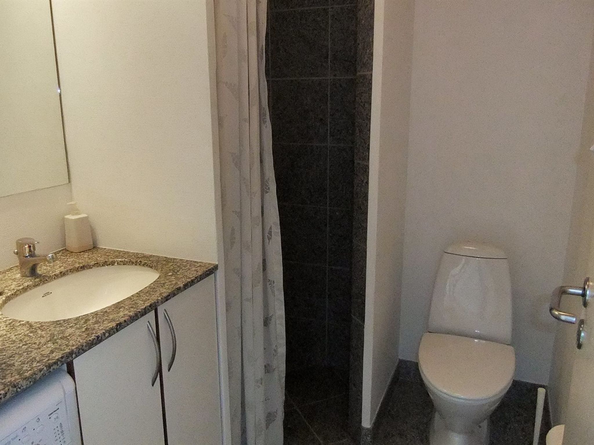 Ein Badezimmer mit einem weißen Waschbecken, einer Toilette und einer Duschkabine.
