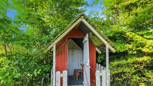 A small, rustic wooden structure with a slanted roof and a single door.