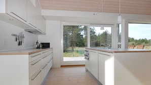 Een moderne keuken met witte kasten, houten aanrecht en een groot raam met uitzicht op de omgeving.