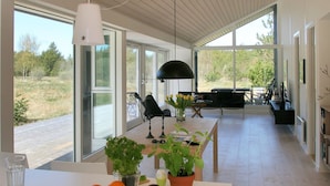 Een moderne keuken met grote ramen, een eethoek met tafel en stoelen, en uitzicht op het omliggende landschap.