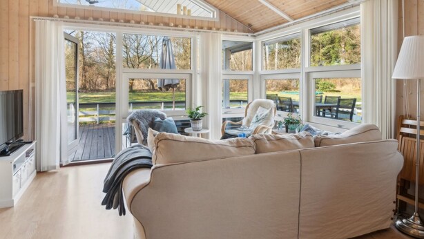 A cozy living room with a large beige sofa, a television, and a view of a garden through large windows. - "Amola" - 1.6km from the sea by Interhome (Højby)